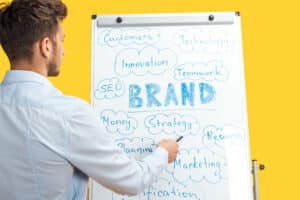 back view of businessman standing near white office board, pointing at words on flipchart