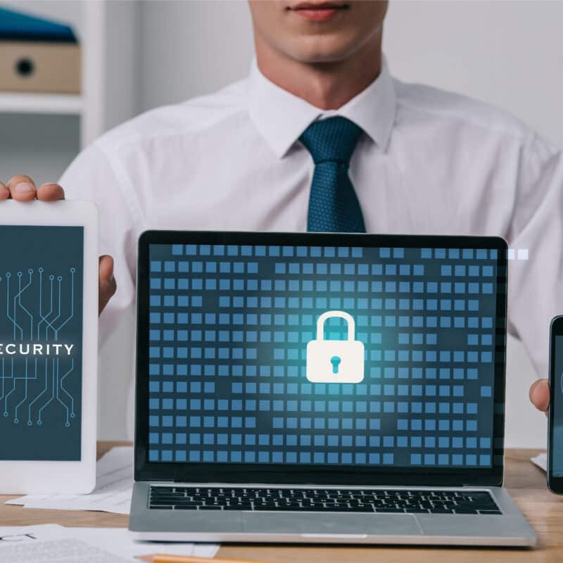 cropped shot of businessman showing laptop, tablet and smartphone with gdpr and cyber security signs