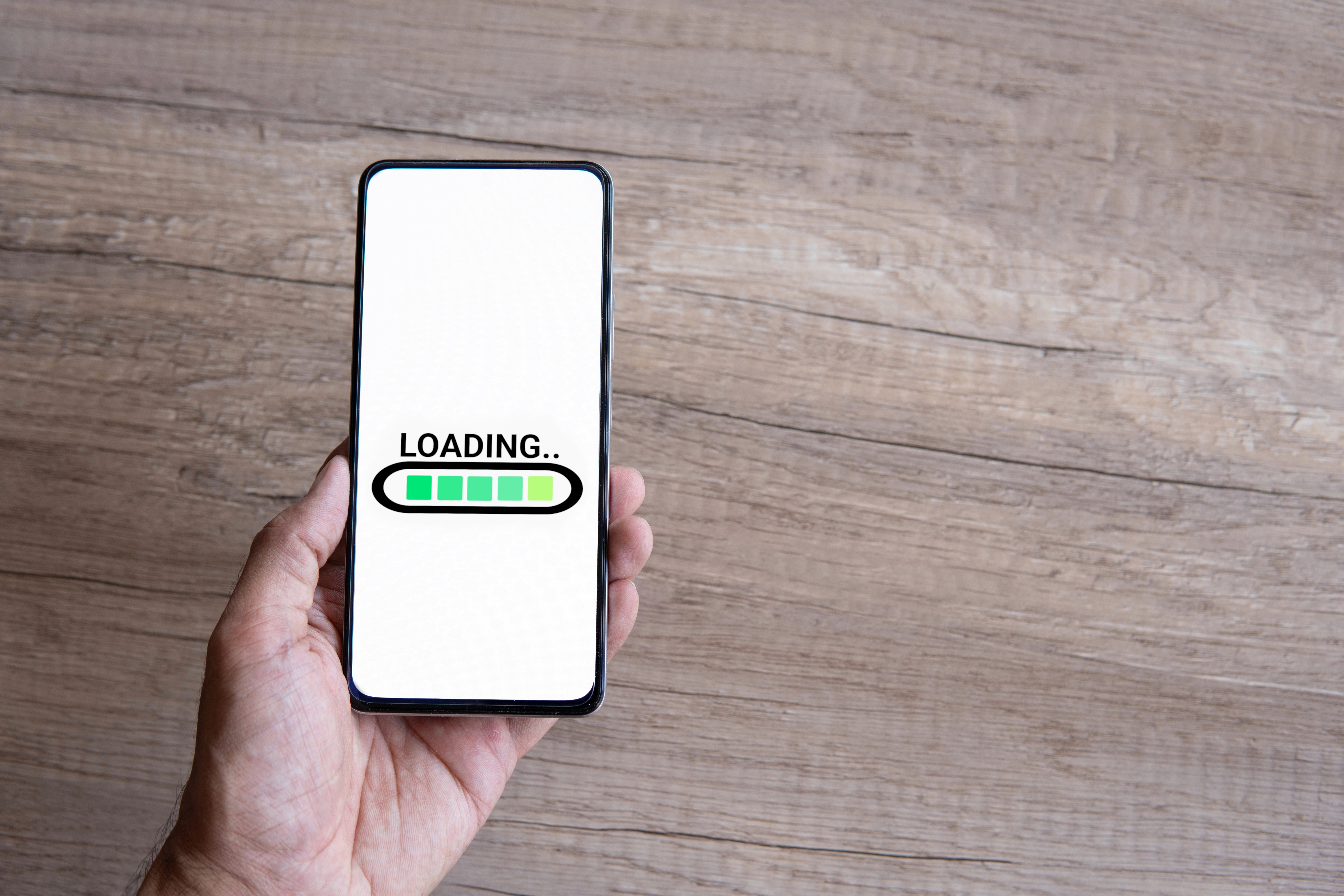 Hand holding smartphone with word LOADING. Copy space for text.