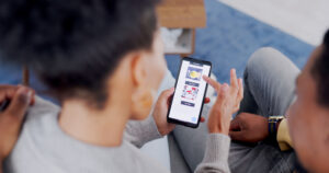 Overhead, phone and a customer couple on a sofa, shopping online in the living room of their home t.