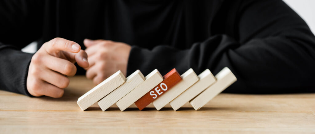 panoramic shot of seo manager pointing with finger at wooden rectangles with lettering seo