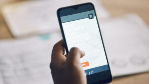 Above closeup hands of african man using a phone while going over paperwork. African american busin.