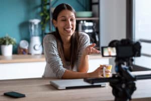 Smiling young woman doing a video blog with the camera while hol