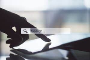 A person’s finger touches a tablet screen with a search bar overlay, suggesting the act of searching or browsing online—perfect for finding the ultimate Blog Strategy Checklist.