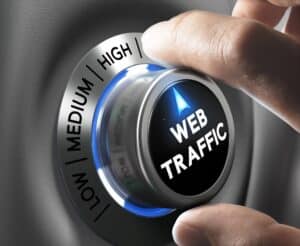 A hand turns a dial labeled "web traffic" from low to high, with indicator points for low, medium, and high—highlighting how Website Design Mistakes San Antonio can impact your site's performance.