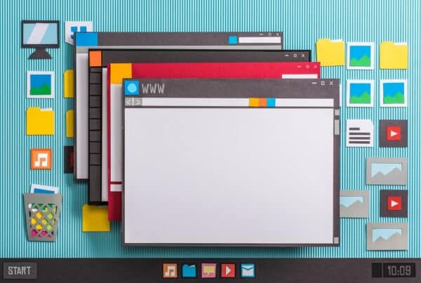Paper cutouts depict overlapping computer windows with icons for folders, images, and apps on a blue striped background, resembling a desktop interface crafted by a San Antonio Web Design Company.