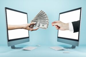 Two computer monitors face each other; one hand extends cash from a screen, while another hand—perhaps with Website Design Questions in mind—reaches out from the opposite monitor.