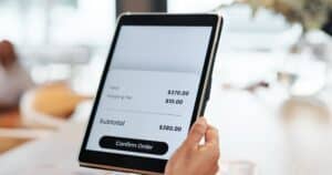 A person holds a tablet displaying an online checkout screen, showcasing E-Commerce Web Design in San Antonio with a subtotal of $380 and a prominent "Confirm Order" button.