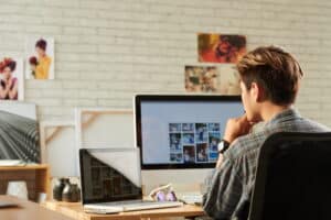Person working on images shown on a computer monitor in front of him.
