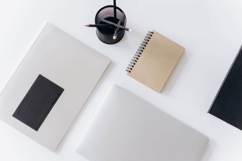 Minimal white desk with notebooks and a pen holder, representing a written SEO scope of work