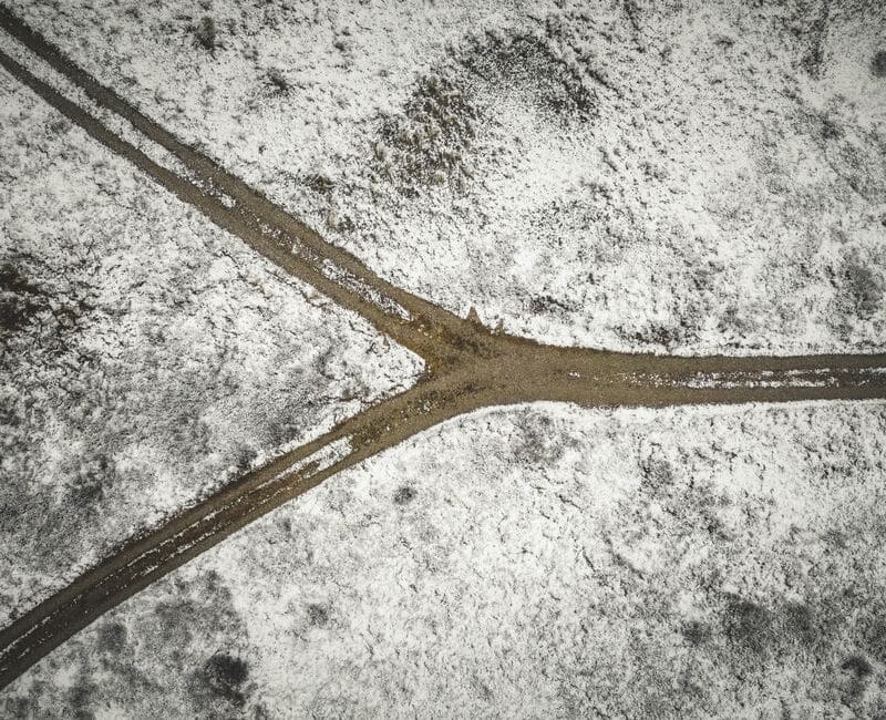 Aerial view of a dirt road splitting in two, representing the choice between Google Ads and SEO