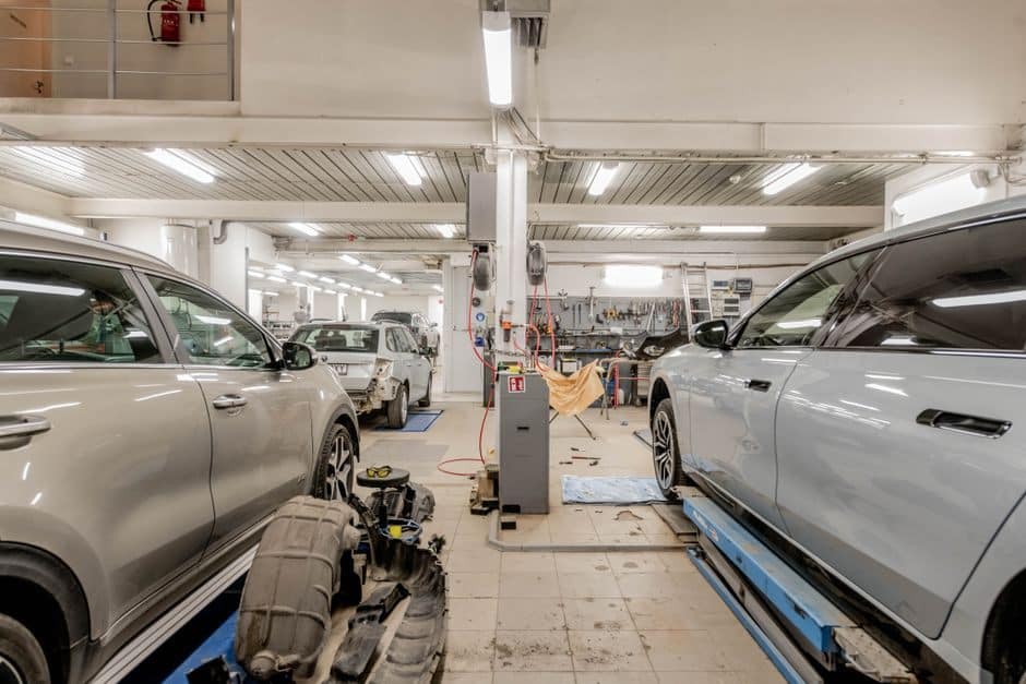 Multi-bay automotive workshop with several vehicles on lifts during service