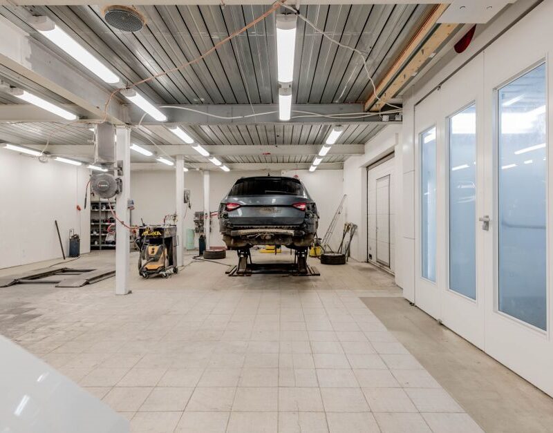 Clean auto repair shop service bay with a vehicle raised on a hydraulic lift