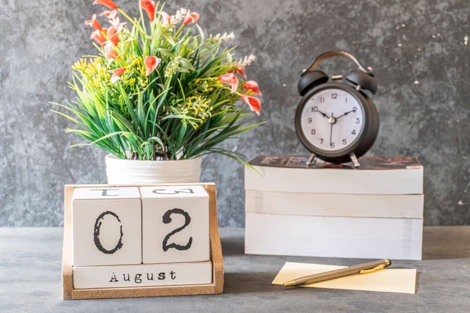 Wooden date blocks and an alarm clock on a desk beside stacked books