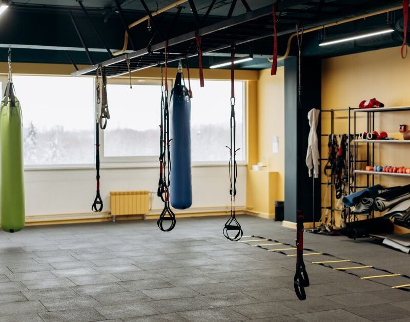 Functional training area in a fitness studio with punching bags and suspension straps