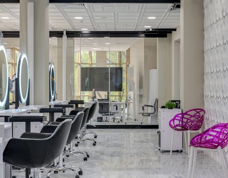 Modern hair salon interior with a row of styling stations and lit round mirrors