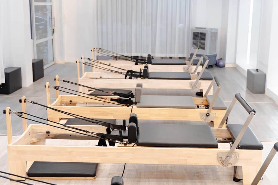 Bright Pilates studio with a row of wooden reformer machines ready for class