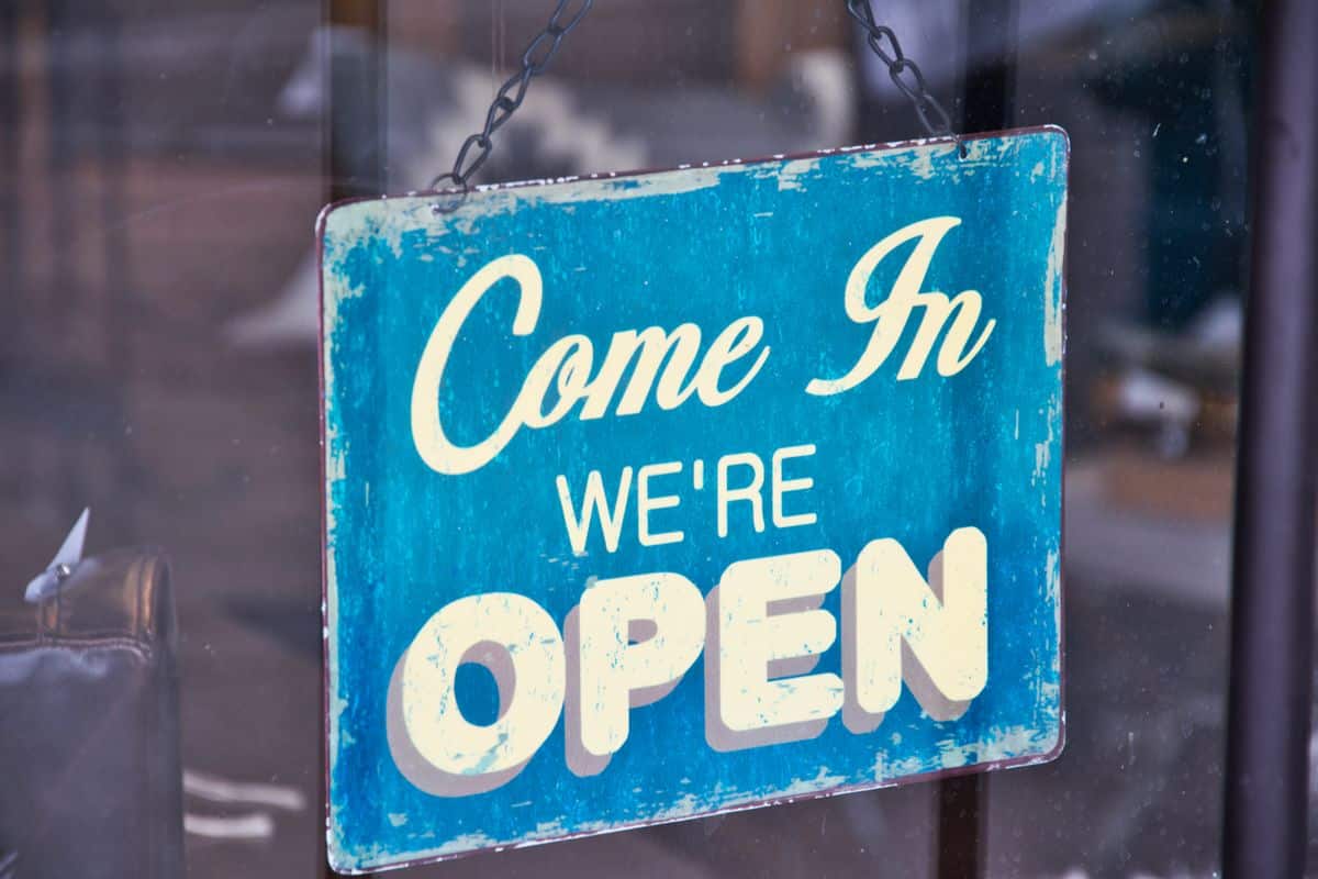 Blue Come In We Are Open sign hanging on a small business glass door
