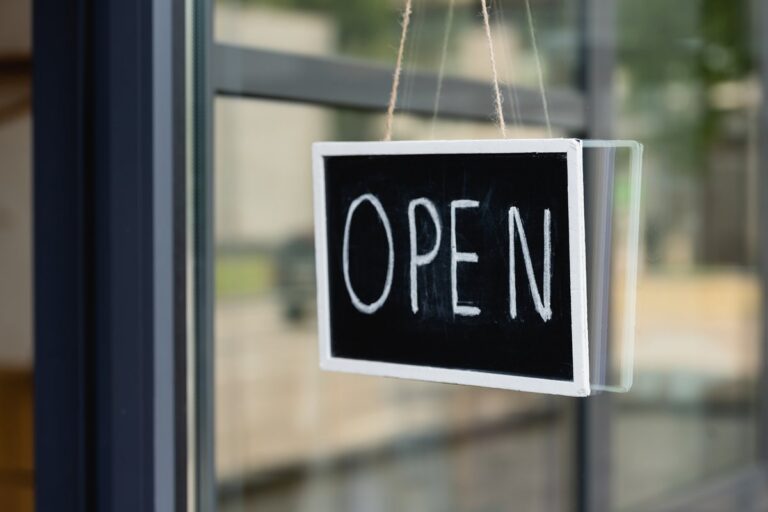 Open sign hanging in the glass window of a local business